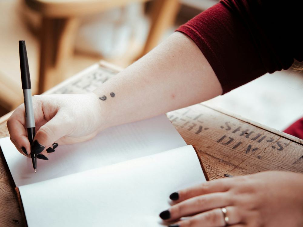 Hand writing in a notebook at a wooden desk