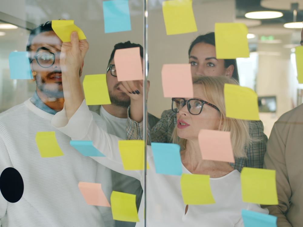Creative team brainstorming with sticky notes on a glass wall